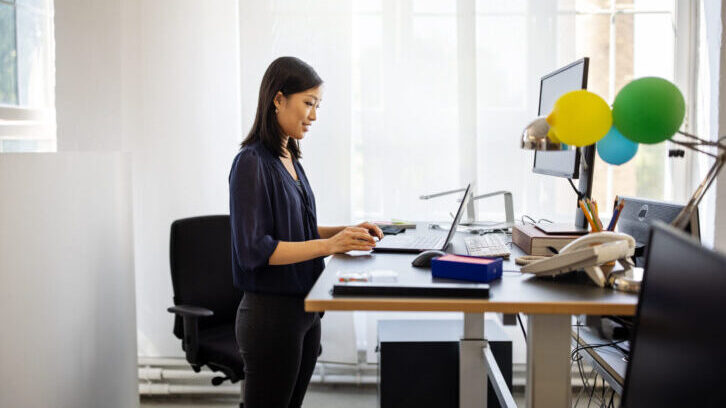 Woman Stading Up Infront of Computer Desk