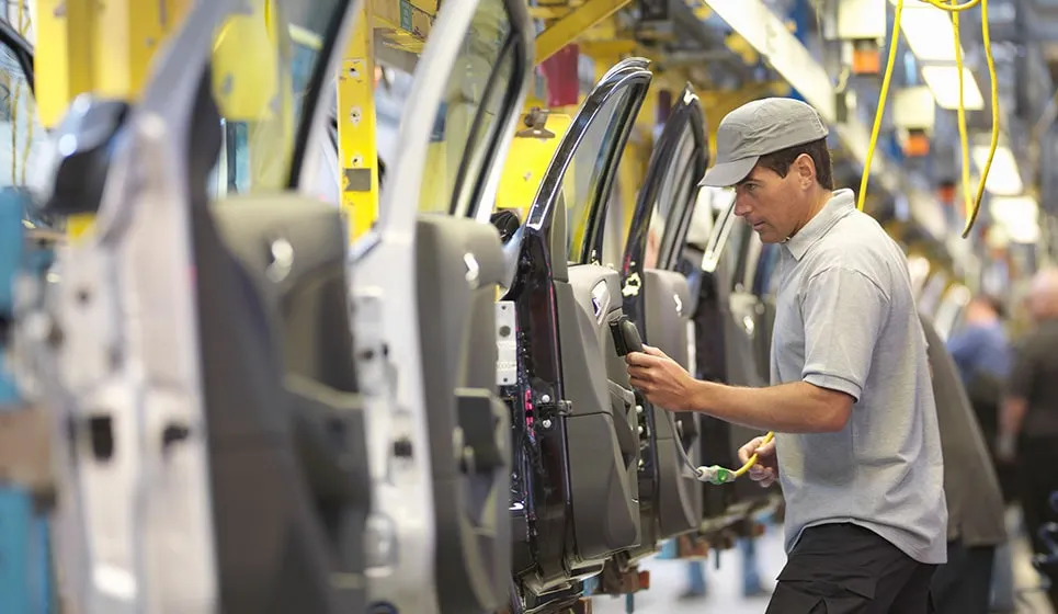Automotive male employee working on a car production line for ergonomics