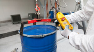 Worker Using Drum Lifter In Warehouse