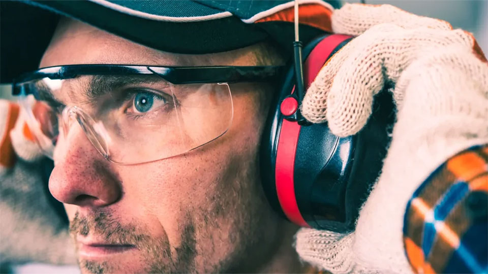 Worker puts on hearing protection as part of IH program.