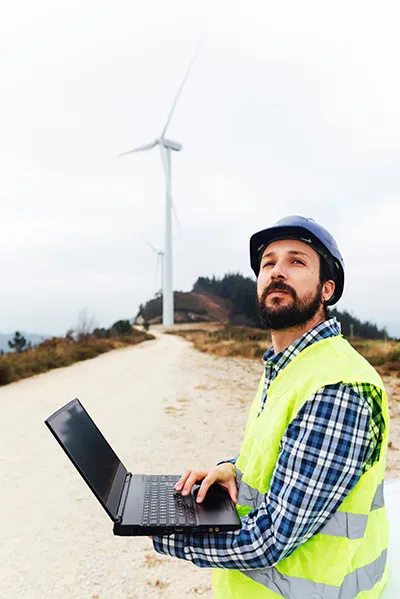 ESG Manager looking up at sustainable wind turbines