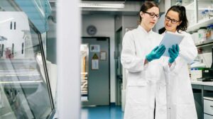two female laboratory scientists discussing data on a tablet device
