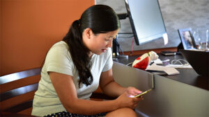 female seated at chair with mobile device