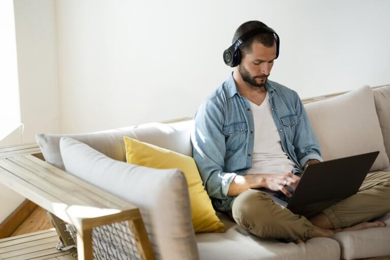 Man sitting on couch working on laptop