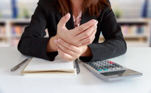female worker rubbing hand with carpal tunnel syndrome