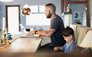 Man Working From Home Next To Son