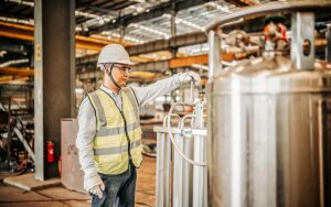 Asian Worker Operating A Gas Tank In A Factory