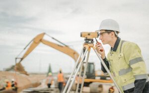Male Engineer Working With Survey Equipment On Construction Site And Worker Background