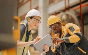 Maintenance Engineers In Safety Gear And Hard Hats Inspect And Test Machines After A Maintenance Program To Ensure They Are Up To Speed On The Production Line At A Steel Fabrication Plant Or Steel Industry.