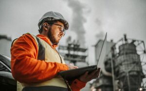 Serious Handsome Engineer Using A Laptop While Working In The Oil And Gas Industry.