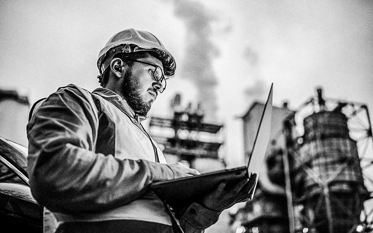 Serious Handsome Engineer Using A Laptop While Working In The Oil And Gas Industry.