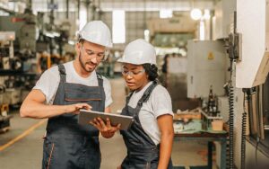 Engineers Reviewing Data On Tablet In Factory