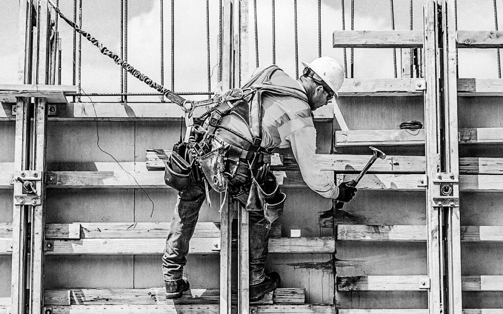 Caucasian Worker Hammering Wood At Construction Site