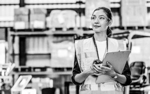 Portrait Of Female Warehouse Supervisor Working In Leading Distribution Warehouse. She Having Skilled In Audit Daily Operations, While Controlling And Managing Inventory And Logistics.