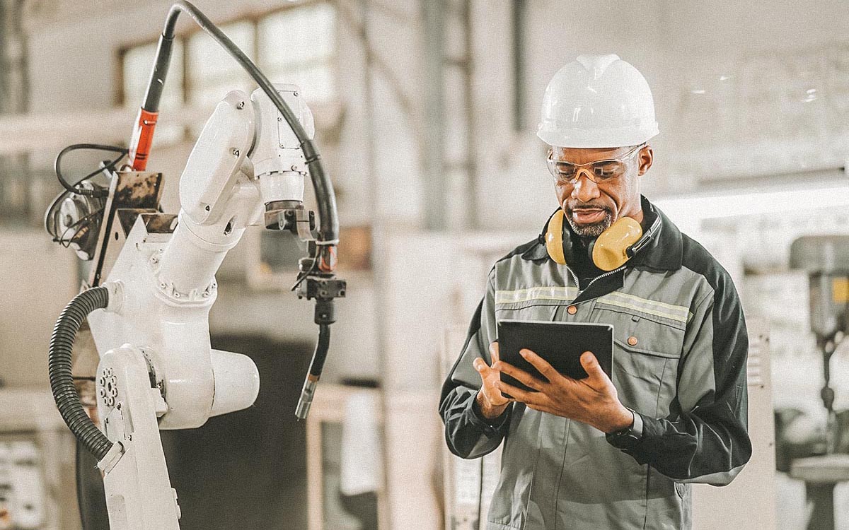African American Engineer Working Automatic Robotic Arm Machine In Factory. Male Technician Worker Maintenance Automatic Robotic Hand In Smart Factory, Industrial And Manufacturing Concept.